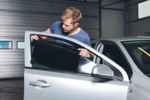 Applying tinting foil onto a car window in a workshop