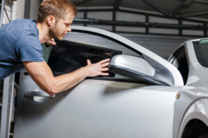 Applying tinting foil onto a car window in a workshop